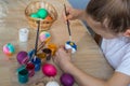 The child holds the painted eggs. A girl in a white T-shirt paints Easter colored eggs with paints and a brush close-up. Spring. Royalty Free Stock Photo