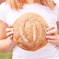 Child holds round bread. Healthy food. Carrying big fresh baker bun