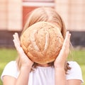 Child holds round bread. Healthy food. Carrying big fresh baker bun