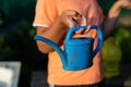 A child holds a small blue watering can in his hand in the garden. Close-up. The child filled the watering can with Royalty Free Stock Photo