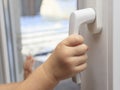 The child holds on to the handle of the window trying to open it. The concept of leaving only children at home, the safety of Royalty Free Stock Photo