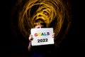 The child holds the word goals 2022 for the new year on a dark background with blurred lights