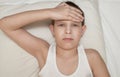 The child at home lies sick under a blanket with a temperature on his back with a sore head in a mask with flu and virus