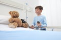 Child in hospital room playing with a sphygmomanometer and a teddy bear imitating doctor Royalty Free Stock Photo