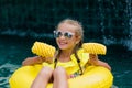 Child with inflatable toy ring float in swimming pool. Little Girl with pineapple lying on a rubber ring in the pool of tropical Royalty Free Stock Photo