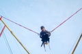 The boy is jumping on a bungee trampoline. A child with insurance and stretchable rubber bands hangs against the sky. The concept Royalty Free Stock Photo