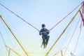 The boy is jumping on a bungee trampoline. A child with insurance and stretchable rubber bands hangs against the sky. The concept Royalty Free Stock Photo