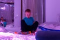 Child with intellectual disability in sensory stimulating room, snoezelen. Autistic child interacting during therapy session.