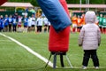 A child in a jacket stands at the edge of the football field behind the team on the other side Royalty Free Stock Photo