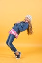 Child in jeans suit, hat, plaid shirt balance tiptoe