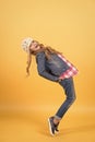 Child in jeans suit, hat, plaid shirt balance tiptoe