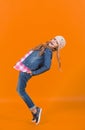 Child in jeans suit, hat, plaid shirt balance tiptoe