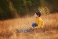 Child in the jeans and yellow sweater in the autumn landscape. Boy in the grass. Royalty Free Stock Photo