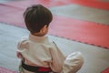 child in a judo uniform sitting on a tatami mat after practice Royalty Free Stock Photo