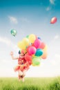 Child jumping with toy balloons in spring field Royalty Free Stock Photo