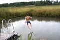 Child jumping from wooden bridge into pond Royalty Free Stock Photo