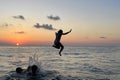 Child jumps in the sea against sunset sky with sun and clouds. Happy family having fun on sea beach Royalty Free Stock Photo