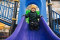 child kid boy playing on slide at playground in the park in autumn Royalty Free Stock Photo