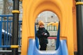 child kid boy playing on slide at playground in the park in autumn Royalty Free Stock Photo