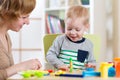 Child kid boy and woman playing colorful clay toy at nursery or kindergarten Royalty Free Stock Photo