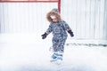 Child kid enjoy learning ice skating on skating rink overcome difficulties in a snowing park during winter holidays Royalty Free Stock Photo