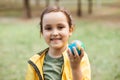 Child kid girl in a yellow raincoat holding globe in a hands outdoor in park or forest. World Earth Day concept. Green Energy, Royalty Free Stock Photo