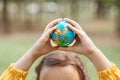 Child kid girl in a yellow raincoat holding globe in a hands outdoor in park or forest. World Earth Day concept. Green Energy, Royalty Free Stock Photo