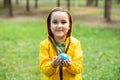 Child kid girl in a yellow raincoat holding globe in a hands outdoor in park or forest. World Earth Day concept. Green Energy, Royalty Free Stock Photo