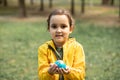 Child kid girl in a yellow raincoat holding globe in a hands outdoor in park or forest. World Earth Day concept. Green Energy, Royalty Free Stock Photo