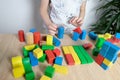 Child, kid plays with colored wooden cubes, builds houses and rockets, concept of development of fine motor skills, tactile