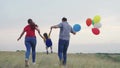 child kid runs with mother father with beautiful colorful balloons. happy family concept. group people running across Royalty Free Stock Photo