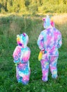 A child in kigurumi. A girl in a rainbow unicorn costume stands outside on a warm summer evening.