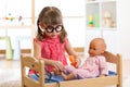 Child in kindergarten. Kid in nursery school. Little girl playing doctor with doll