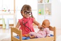 Child in kindergarten. Kid in nursery school. Little girl preschooler playing doctor with doll. Royalty Free Stock Photo