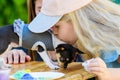 Child kisses a dog, love for pets. girl with long hair and a cap. gift baby dog