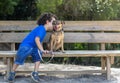 Boy kissing his dog sitting on a wooden bench in the park Royalty Free Stock Photo
