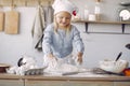 Little girl in a white shef hat cook the dough for cookies