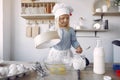 Little girl in a white shef hat cook the dough for cookies