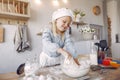 Little girl in a white shef hat cook the dough for cookies