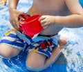 Child kneeling in backyard pool pouring water on himself Royalty Free Stock Photo