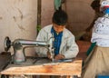 Child labor, boy sewing in booth on the market.