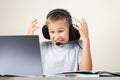 Child with laptop computer and headphones sitting at table with books. E-education, distance learning, Internet, gaming Royalty Free Stock Photo