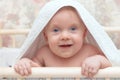 A child with large blue eyes looks into the camera under a white towel / blanket Royalty Free Stock Photo