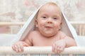 A child with large blue eyes looks into the camera under a white towel / blanket Royalty Free Stock Photo