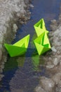 The child launched paper boats made of green paper into the stream in the spring