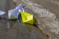 The child launched paper boats made of white and yellow paper into the stream