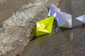 The child launched paper boats made of white and yellow paper into the stream