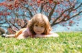 Child laying in grass in summer nature park. Kids face, little boy portrait.