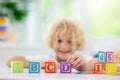 Child learning letters. Kid with wooden abc blocks