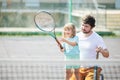 Child learning to play tennis with her father on outdoor court. Little girl with tennis racket